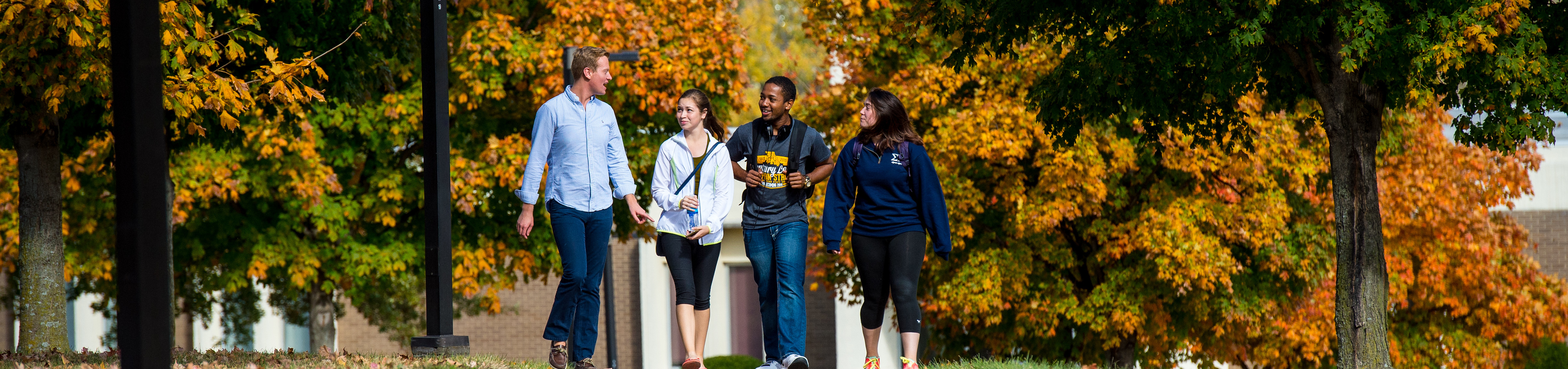 A blonde student with a black shirt gives a thumbs up on a nice day.