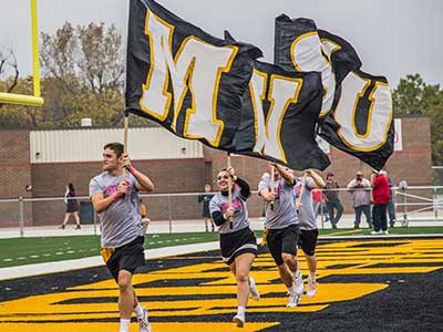 Cheerleaders carry in MWSU flags at a football game