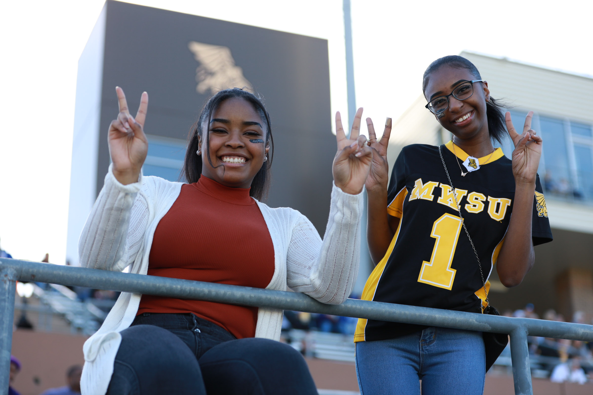 116A8511 two students posing for the camera smiling and holding up peace signs