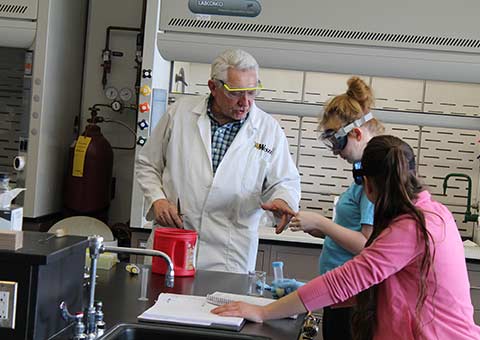 Students working with a professor in a chemistry lab