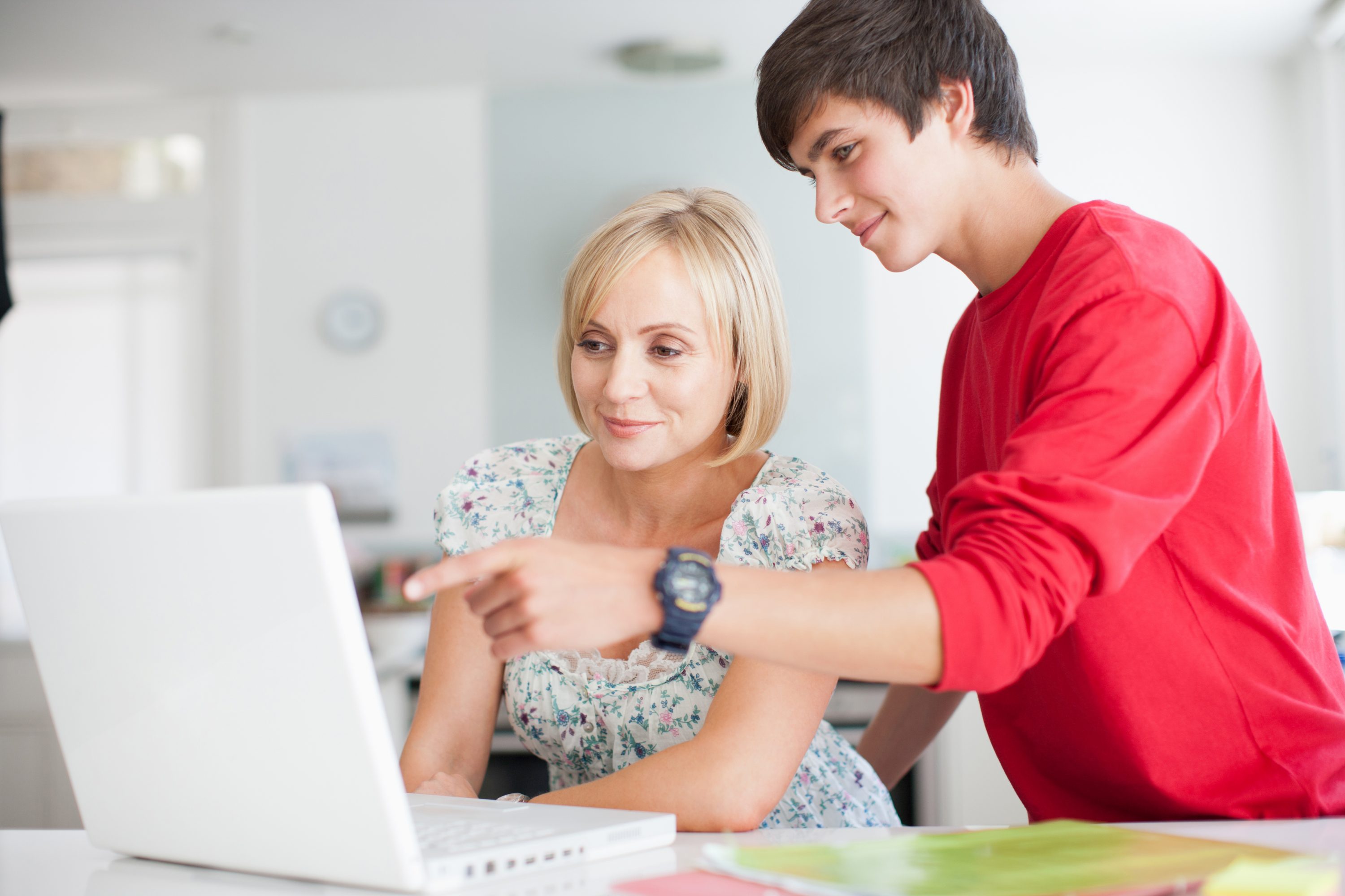 Mother and teenage son using laptop