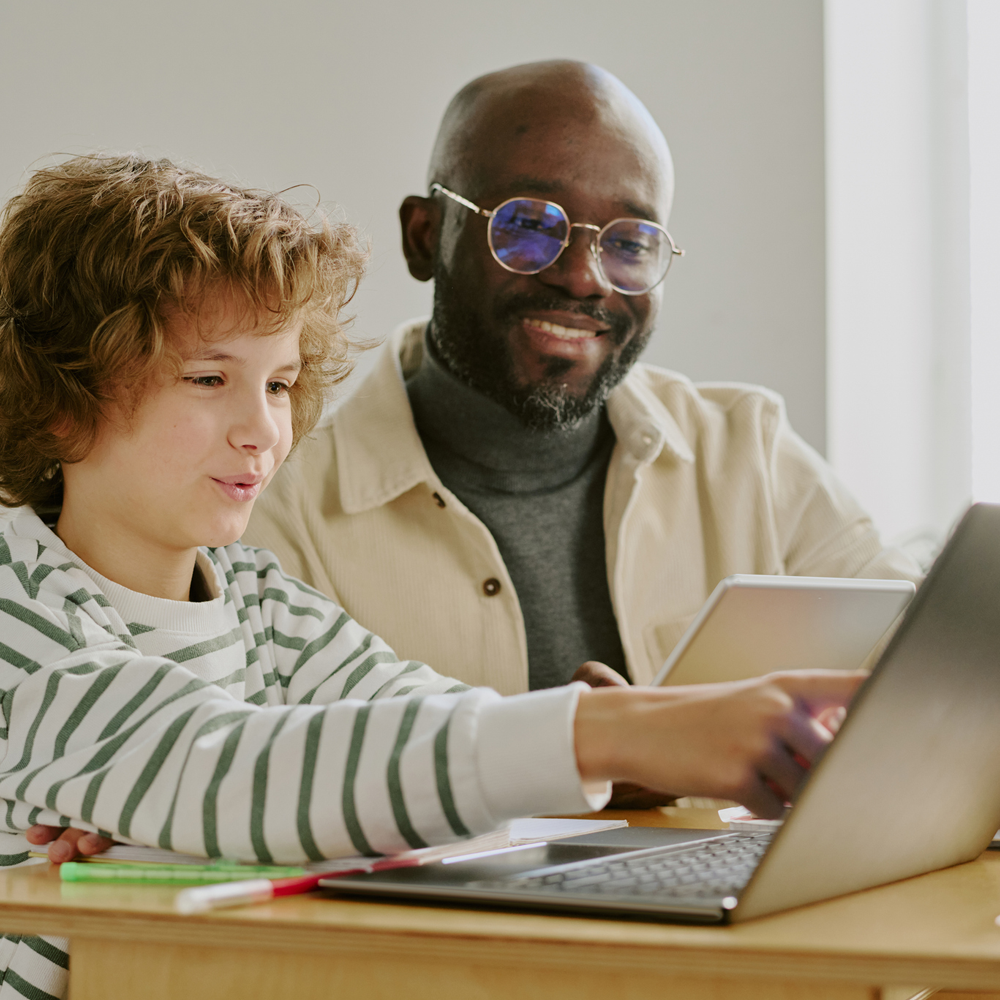 MedSquare2 An instructor with a child smile as they work together on a laptop.