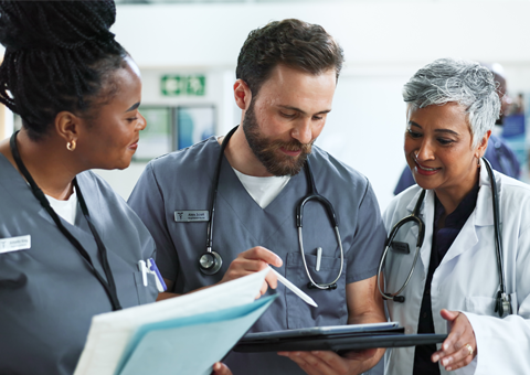 Two nurses and a doctor look over a medical chart