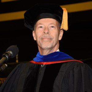 Dr. Doug Davenport standing at podium in regalia