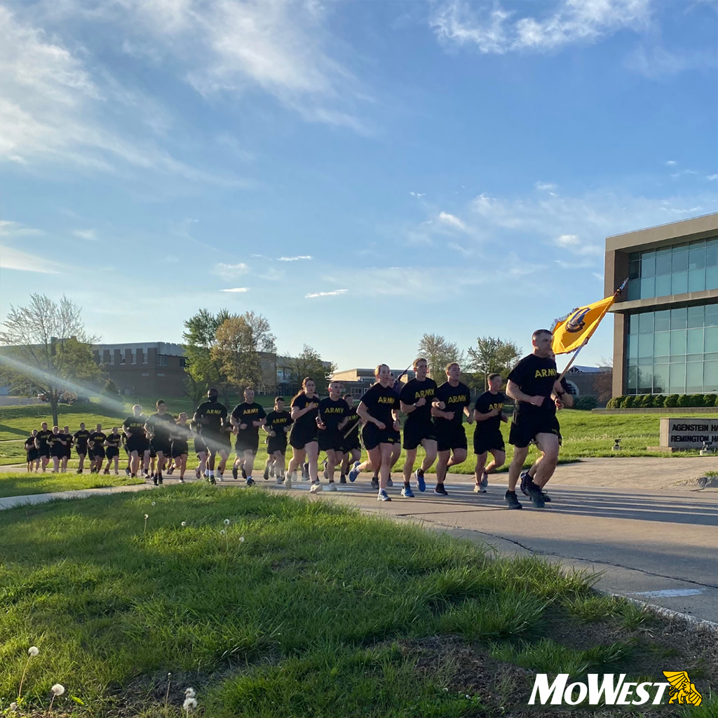 JoggingWithFlag-Updated Army ROTC students jog the MoWest campus single file with a golden flag raised.