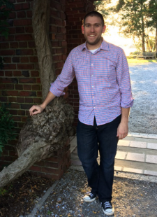 Dr Michael Allen stands in front of a tree and brick wall.