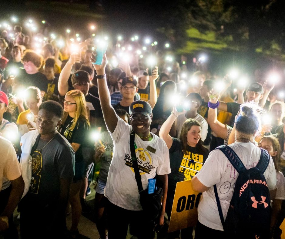 freshmen hold their lit phones above their heads in a "candlelight" ceremony