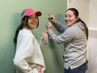 student volunteers installing wall accessory