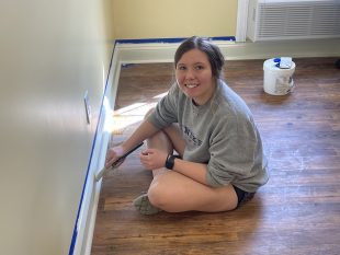 student volunteer painting baseboard