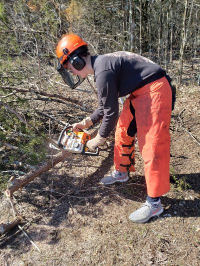 student uses chainsaw