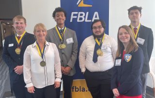 students and adviser in front of FBLA banner