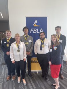 students and adviser in front of FBLA banner