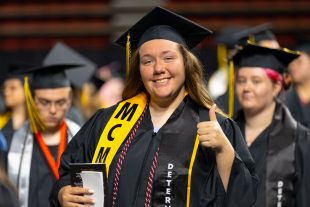 graduate with diploma gives thumbs-up