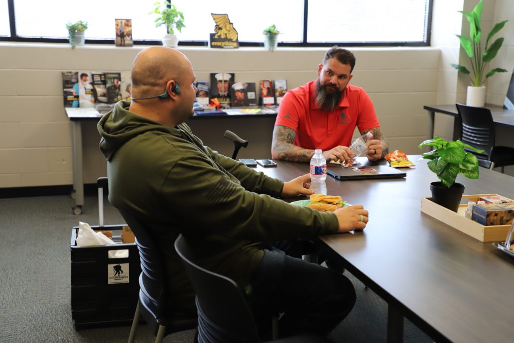 student eats with wounded warrior rep