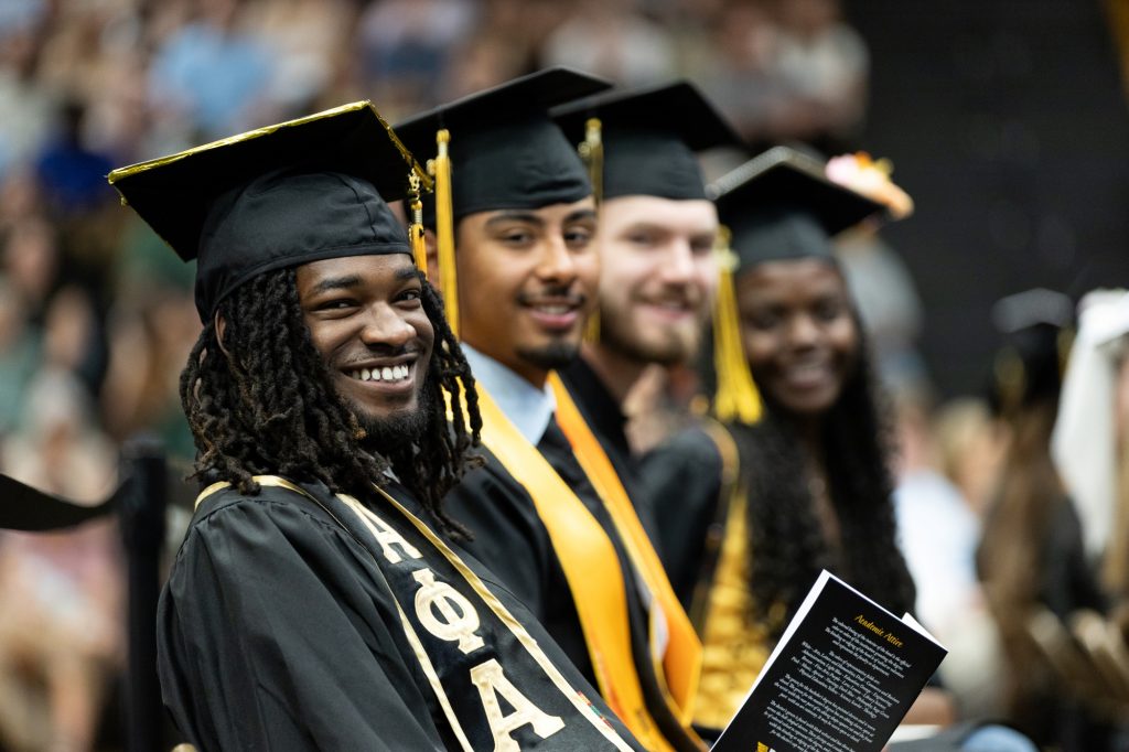 seated graduates smile at camera