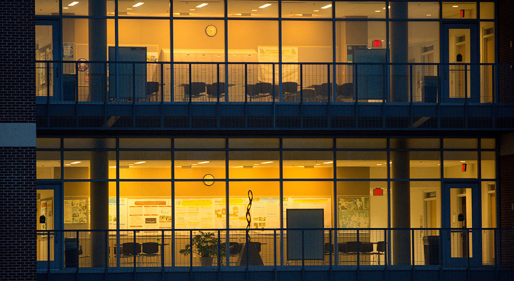 Campus building exterior at night with lights on
