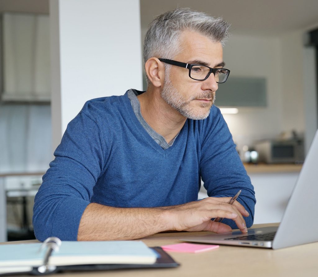 Older man working on laptop at home