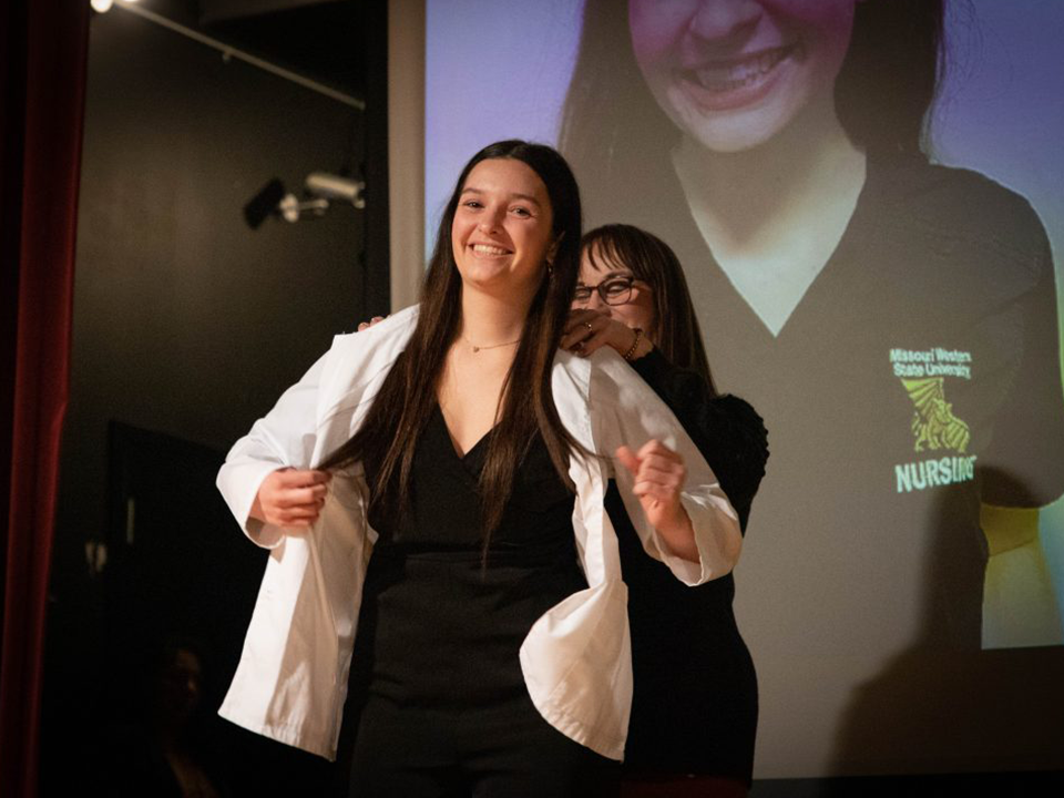 A first-semester nursing student receives a white coat during the Missouri Western Lighting of the Lamp White Coat Ceremony on March 3, 2023.