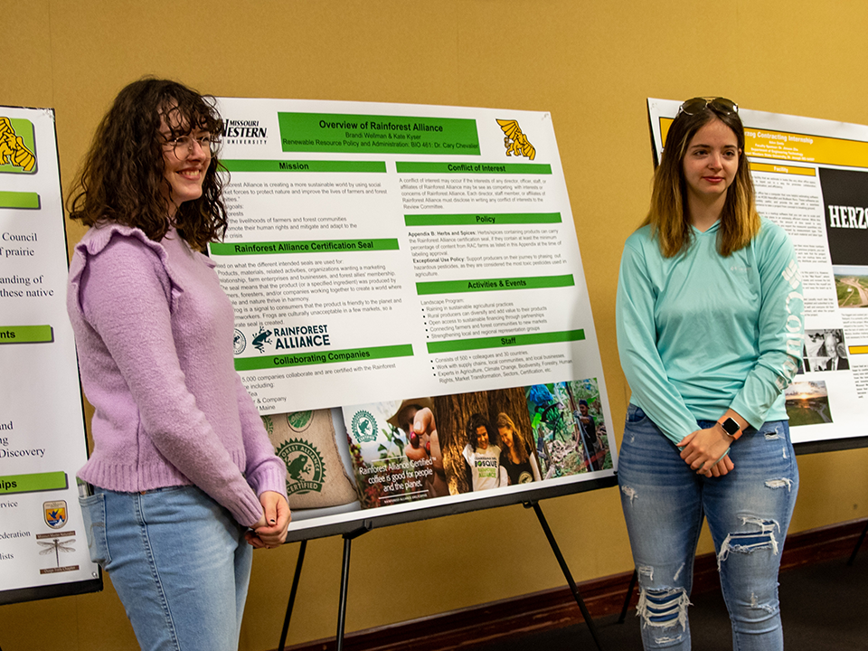 two students posing with their poster at the applied learning showcase