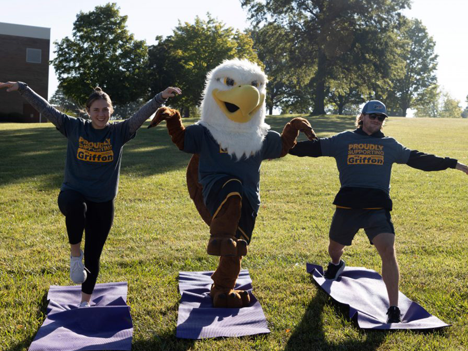 two individuals do yoga with max the griffon during the griffon 360 family walk during family day 2022