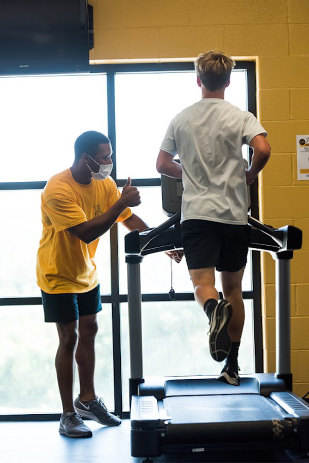 student assistant coaching a student on a treadmill