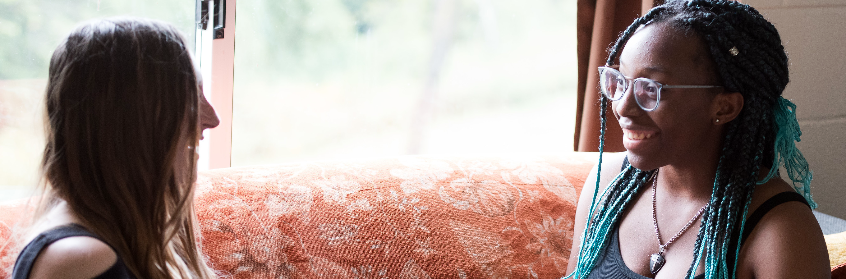 Two students smiling as they hang out in a residence hall.