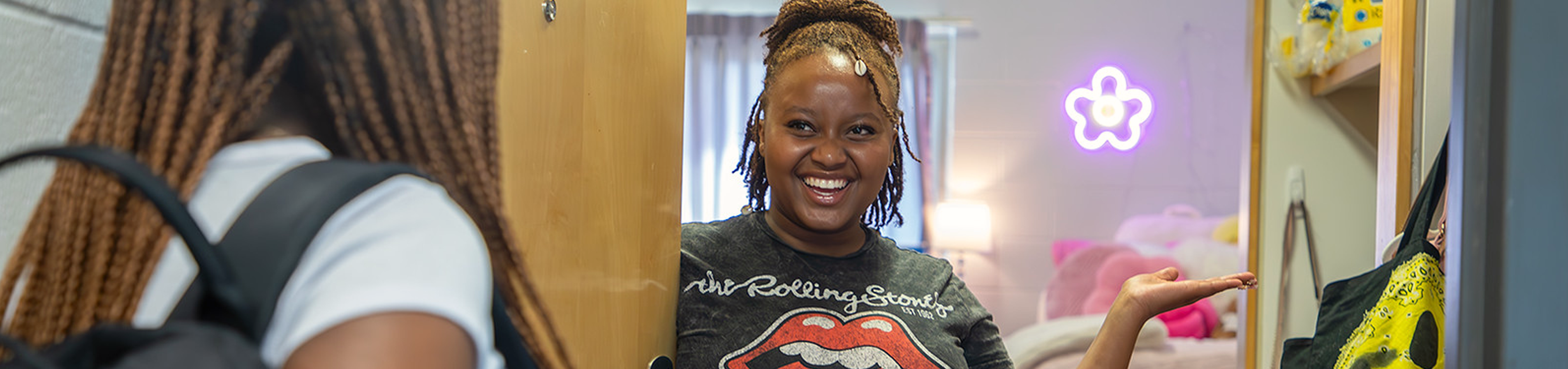 SmilingStudentsResidentialHall Four students sit before a window on campus having a conversation.