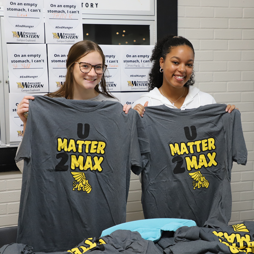 two students holding up u matter 2 max tshirts