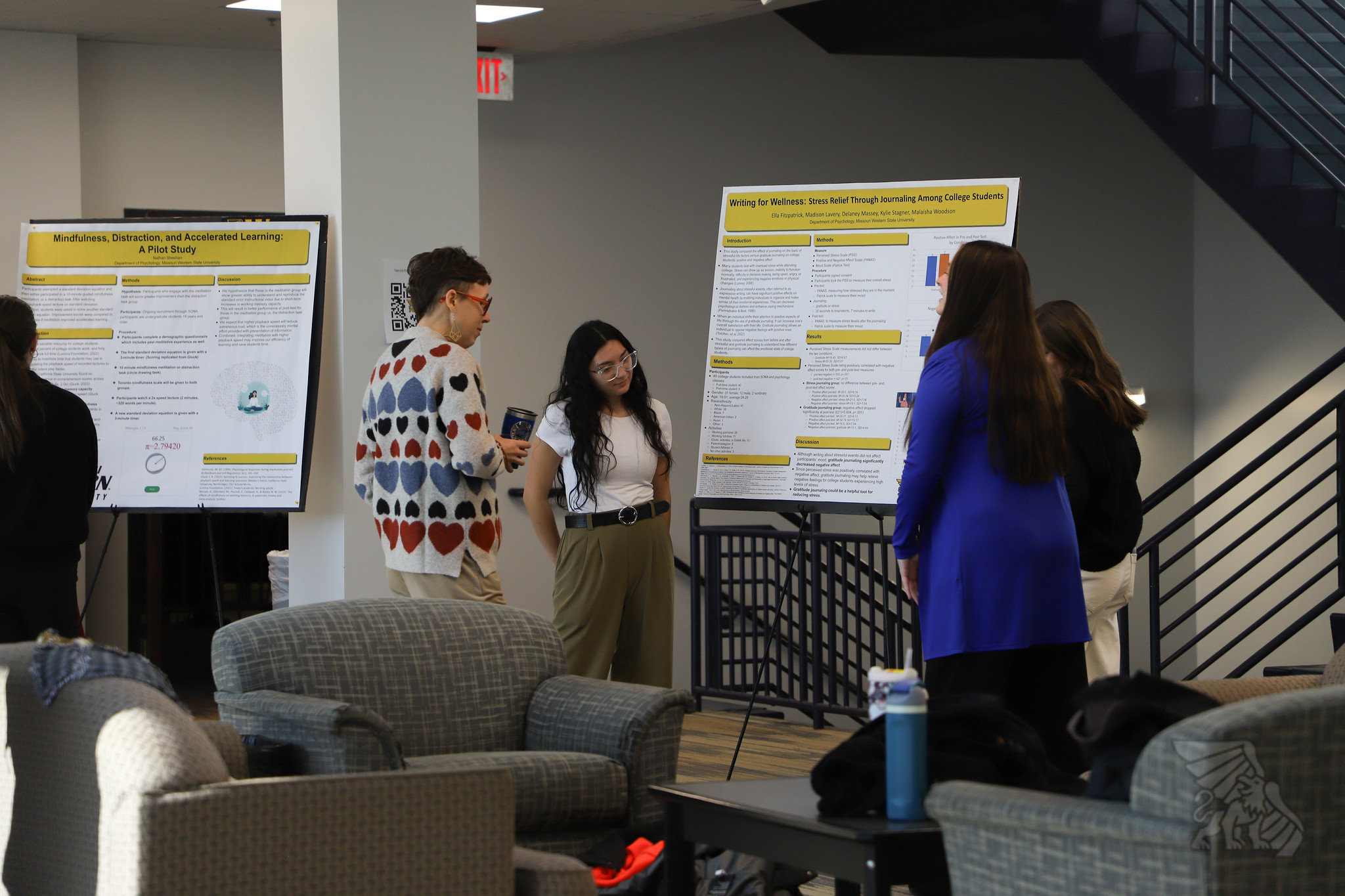 People gather around a poster as a student explains their psychology research.