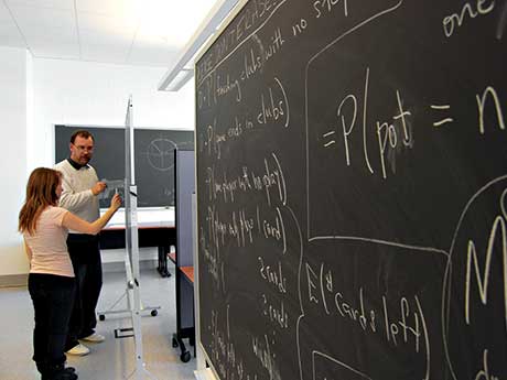 Student and professor work on a math problem on a chalkboard