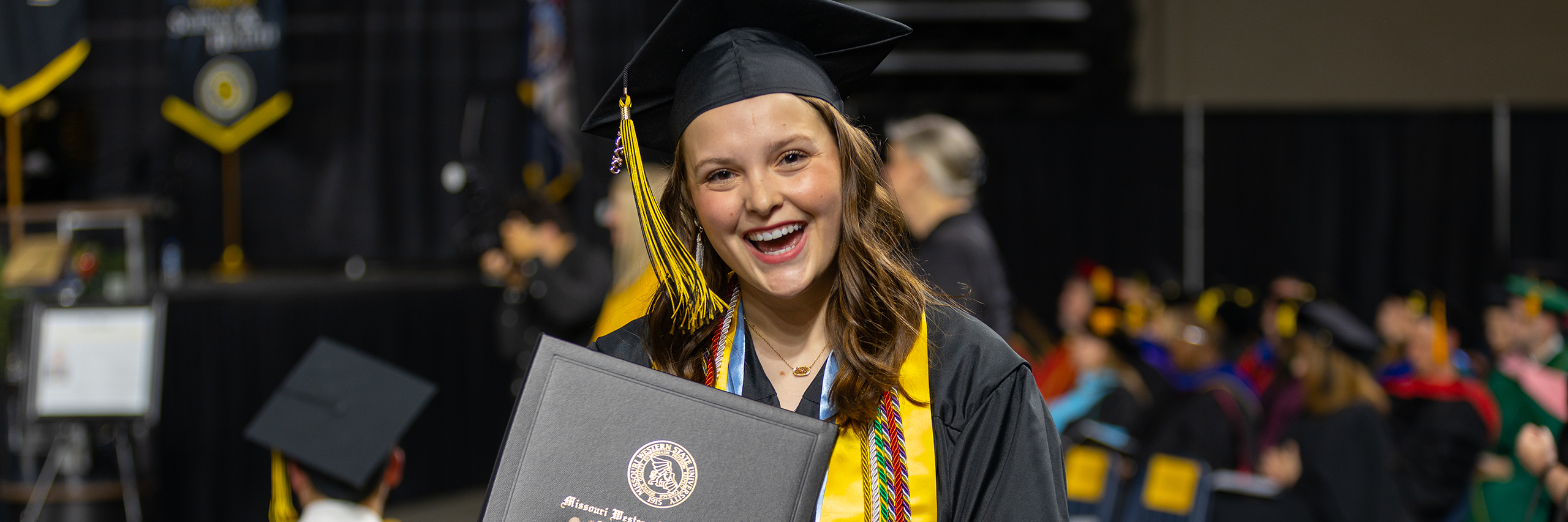 taylor edwards holding her diploma and smiling at commencement