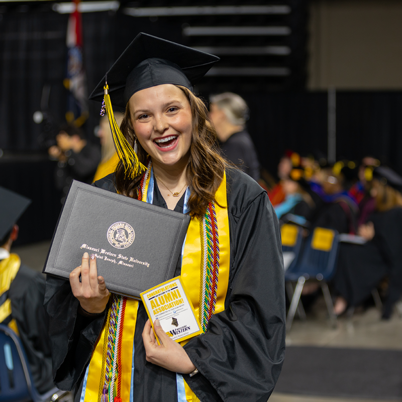 taylor edwards holding diploma and posing for a photo at commencement