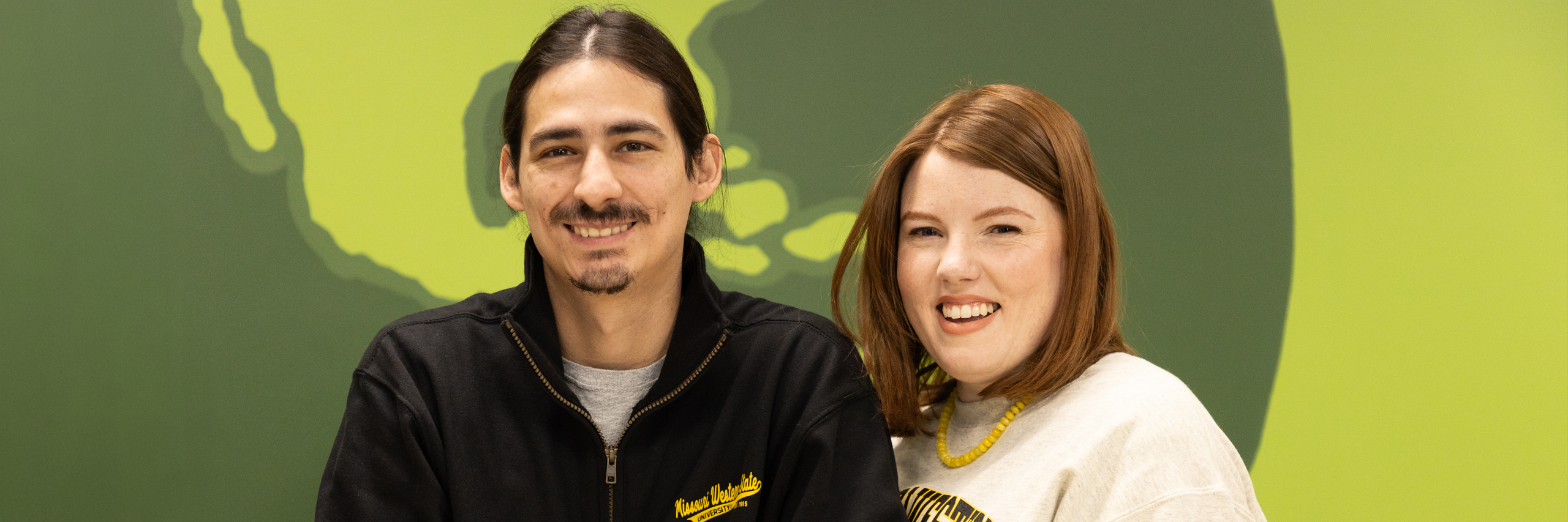 Katelyn Canon '15 and Tommy Johnson 14 stand before a swirled background of lime and olive greens.