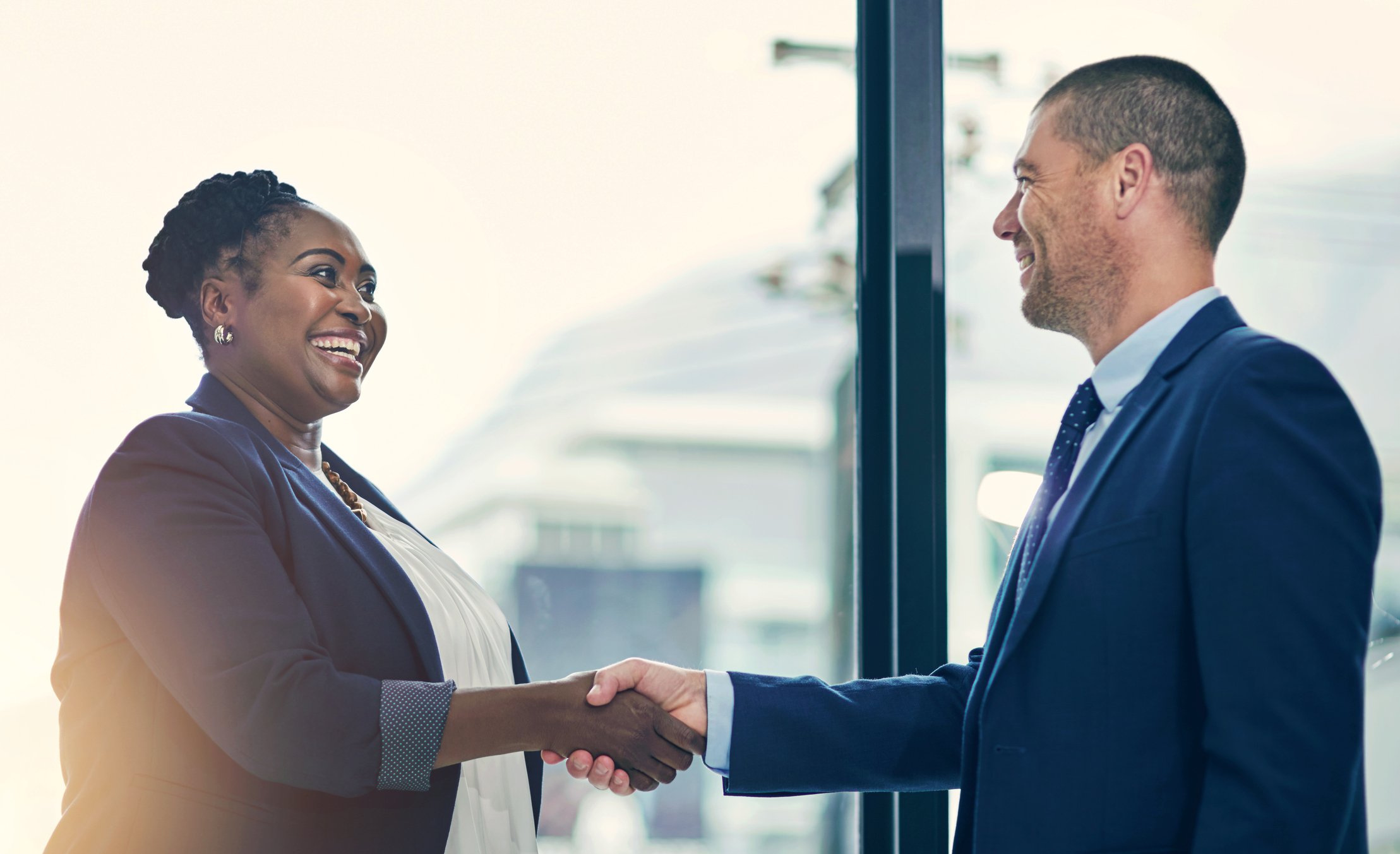 Welcome Aboard A woman smiles as she shakes a man's hand in the office place.