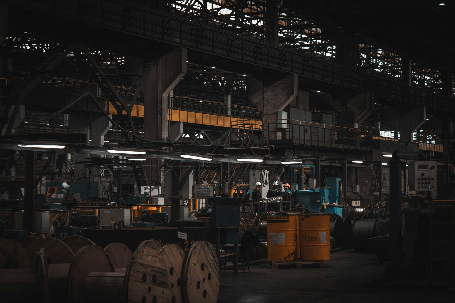 lean workshop a darkened warehouse with three workers speaking under lights.