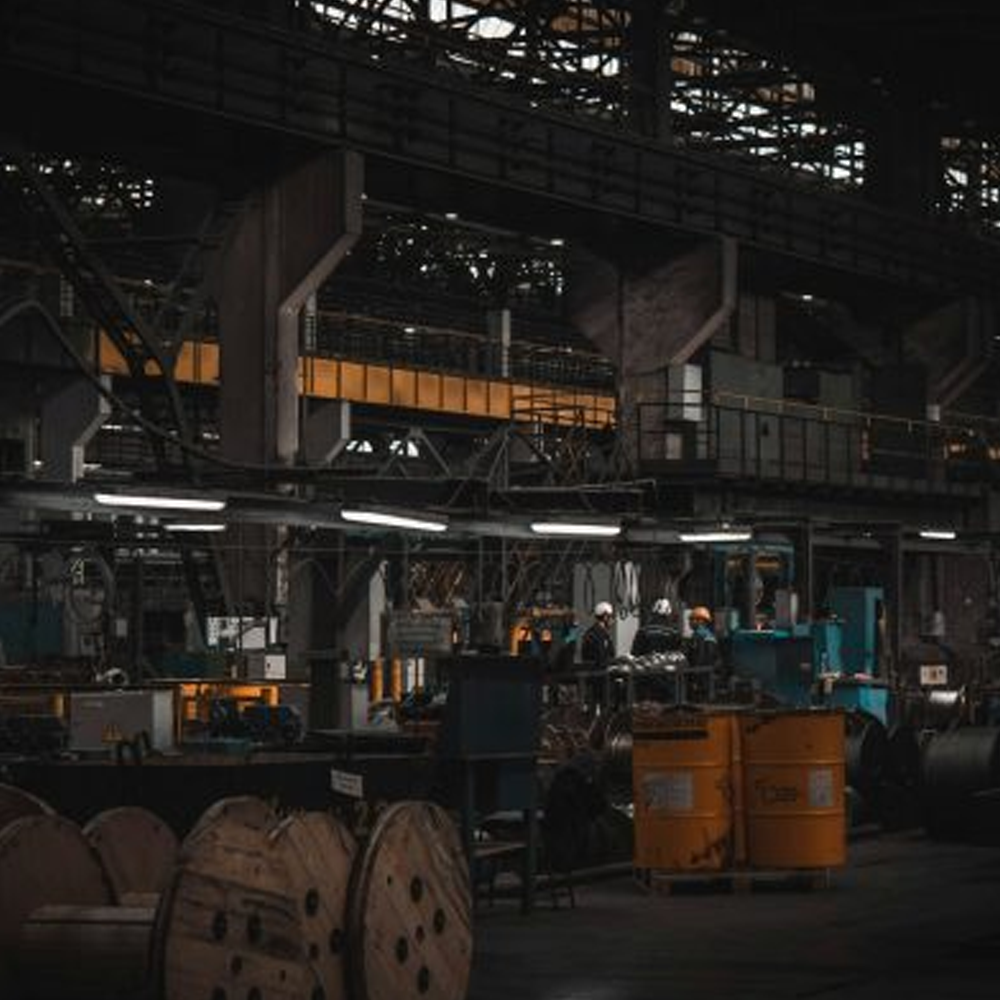 a darkened warehouse with three workers speaking under lights.