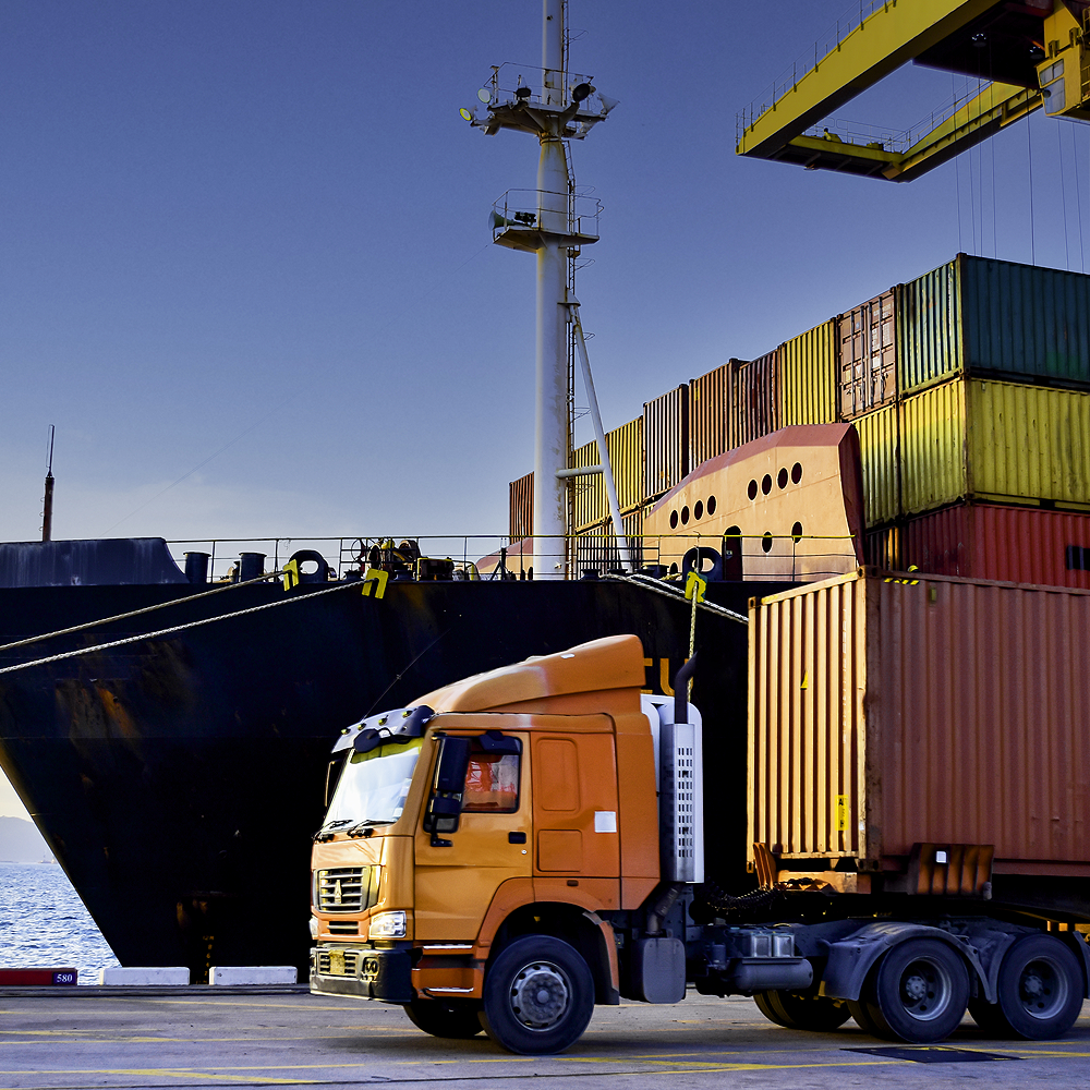 A semi sits at the dock with supply crates on a ship