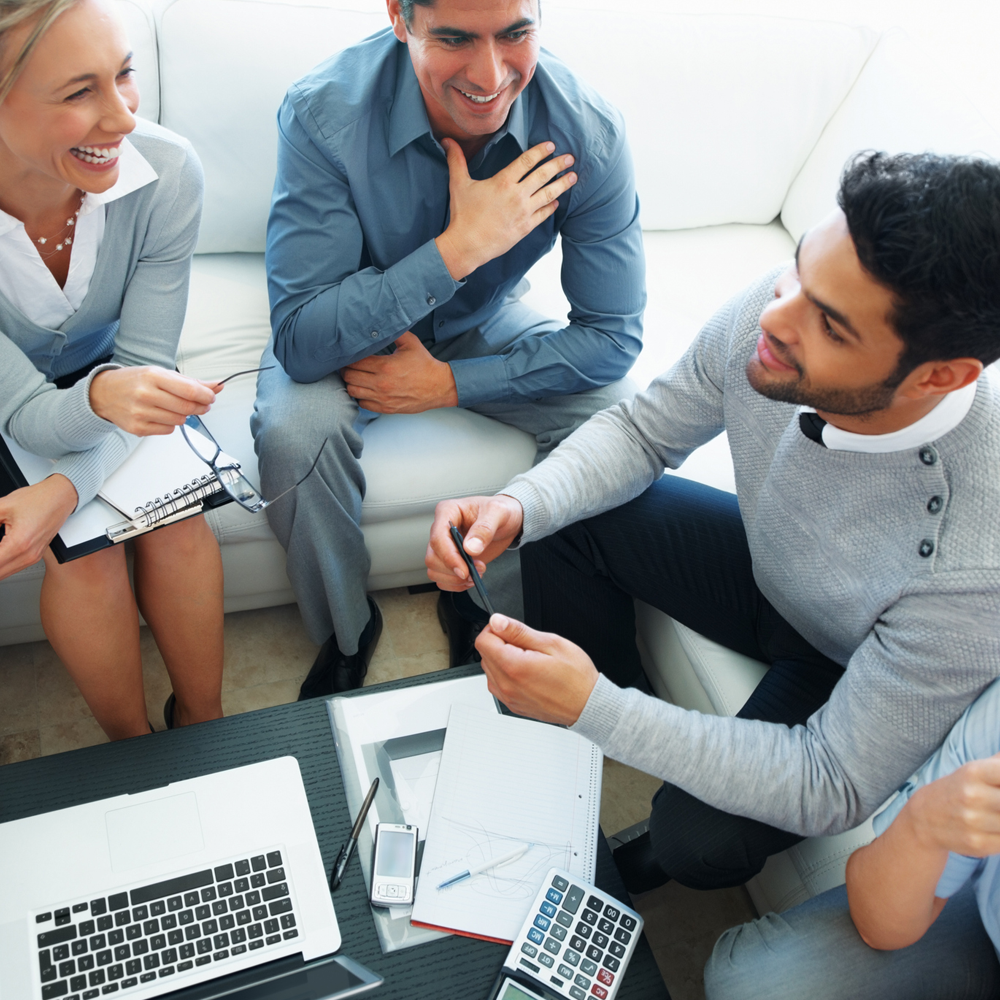 A group of people sit around a table discussing business.