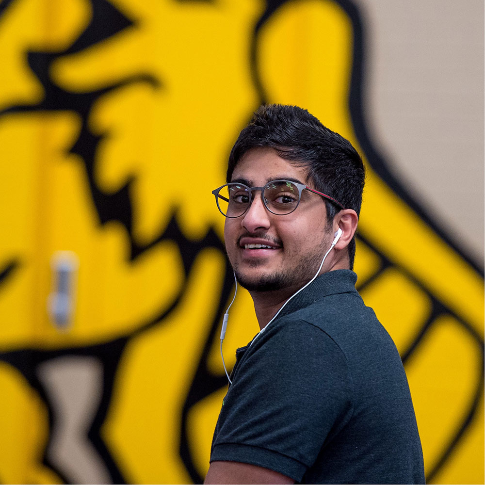 Student with headphones in front of Griffon mural