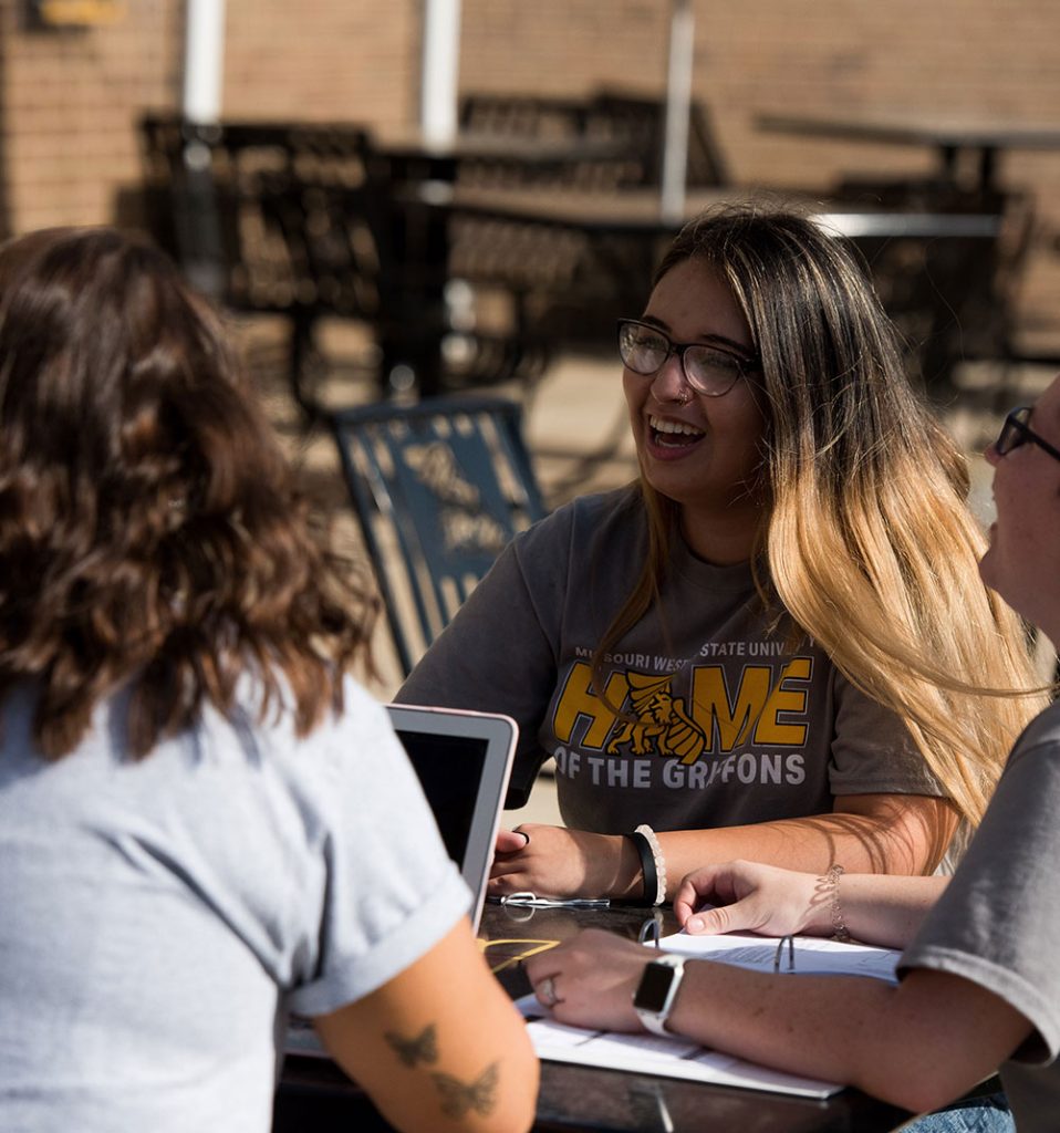 Students sitting at a table outside in the sun