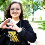 Kaley Dittemore shows Tri Sigma hand sign.