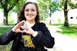 Kaley Dittemore shows Tri Sigma hand sign.