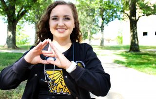 Kaley Dittemore shows Tri Sigma hand sign.